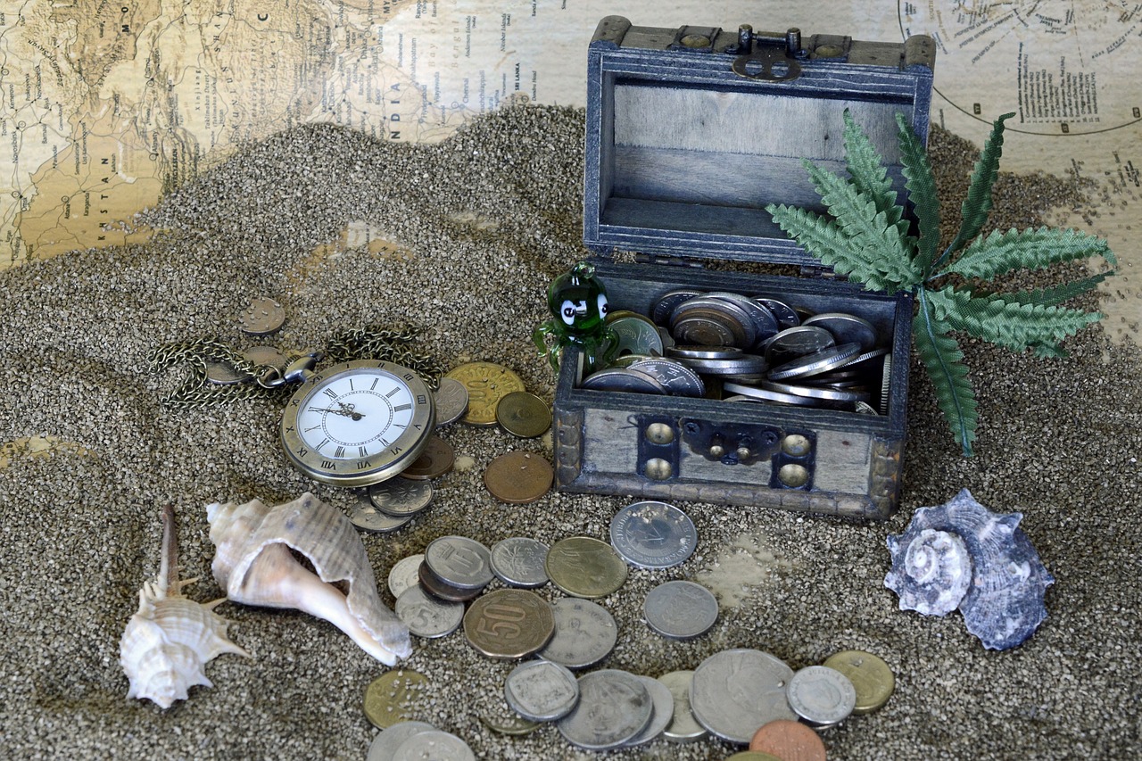 Schatztruhe im Sand mit Müzen und Muscheln